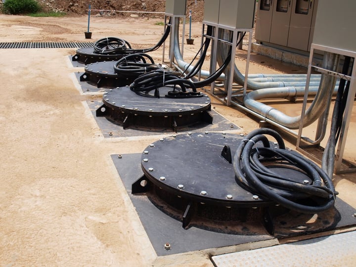 Submersible pump hatches and cables on an outdoor concrete wet well